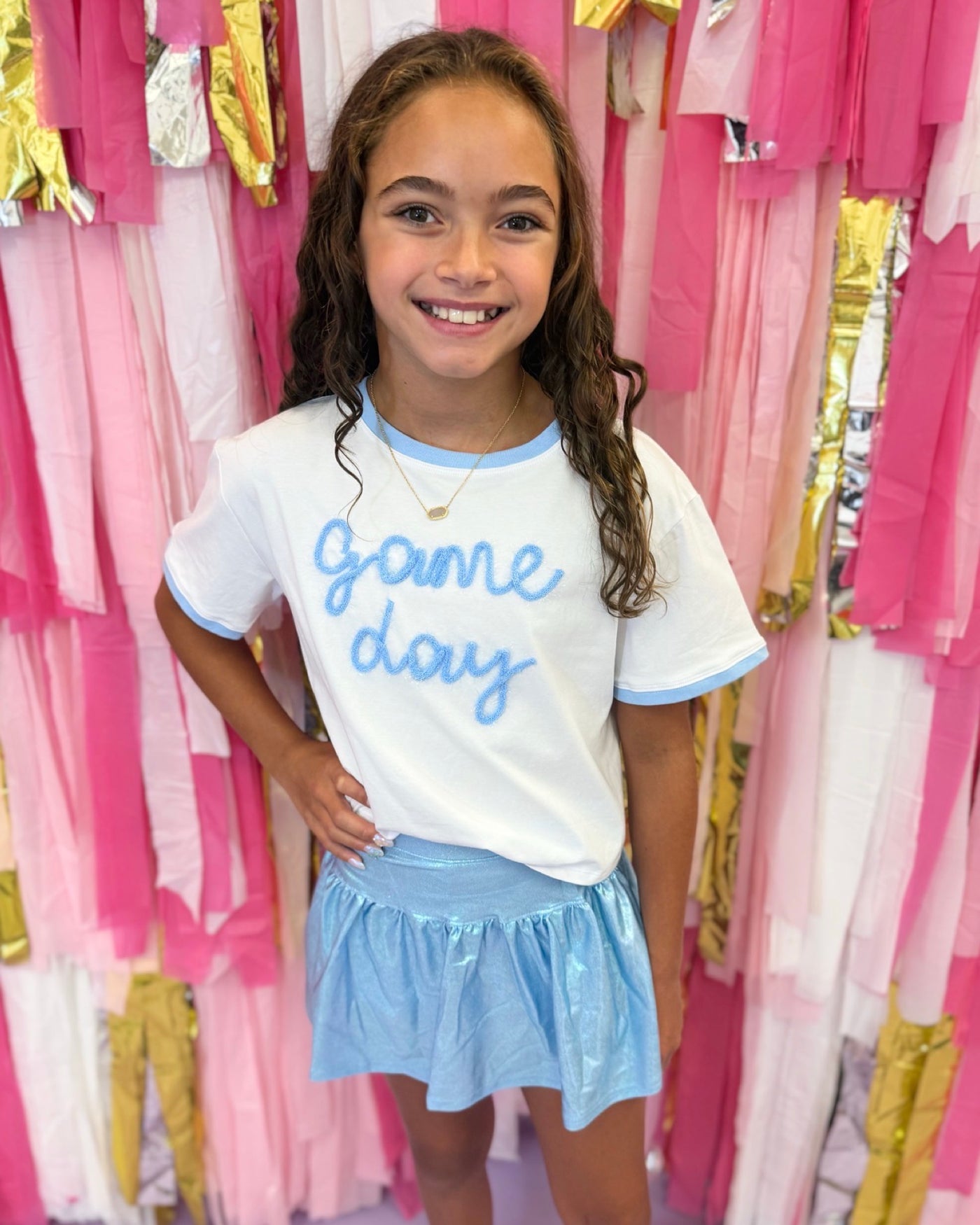 Tween Girl wearing a 'Game Day' shirt in a store with pink and gold decorations